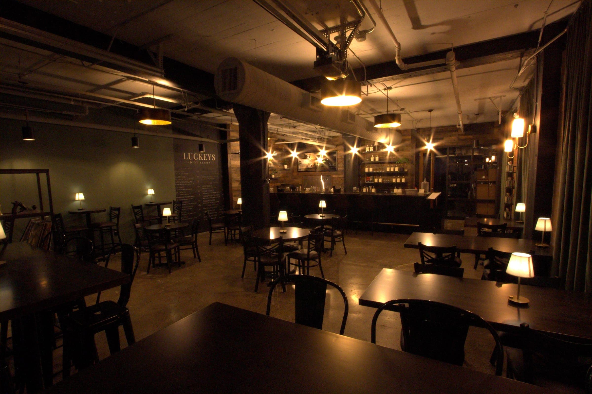 The Luckeys bar room in Peabody after close — tables and lamps lit, the bar glowing at the back
