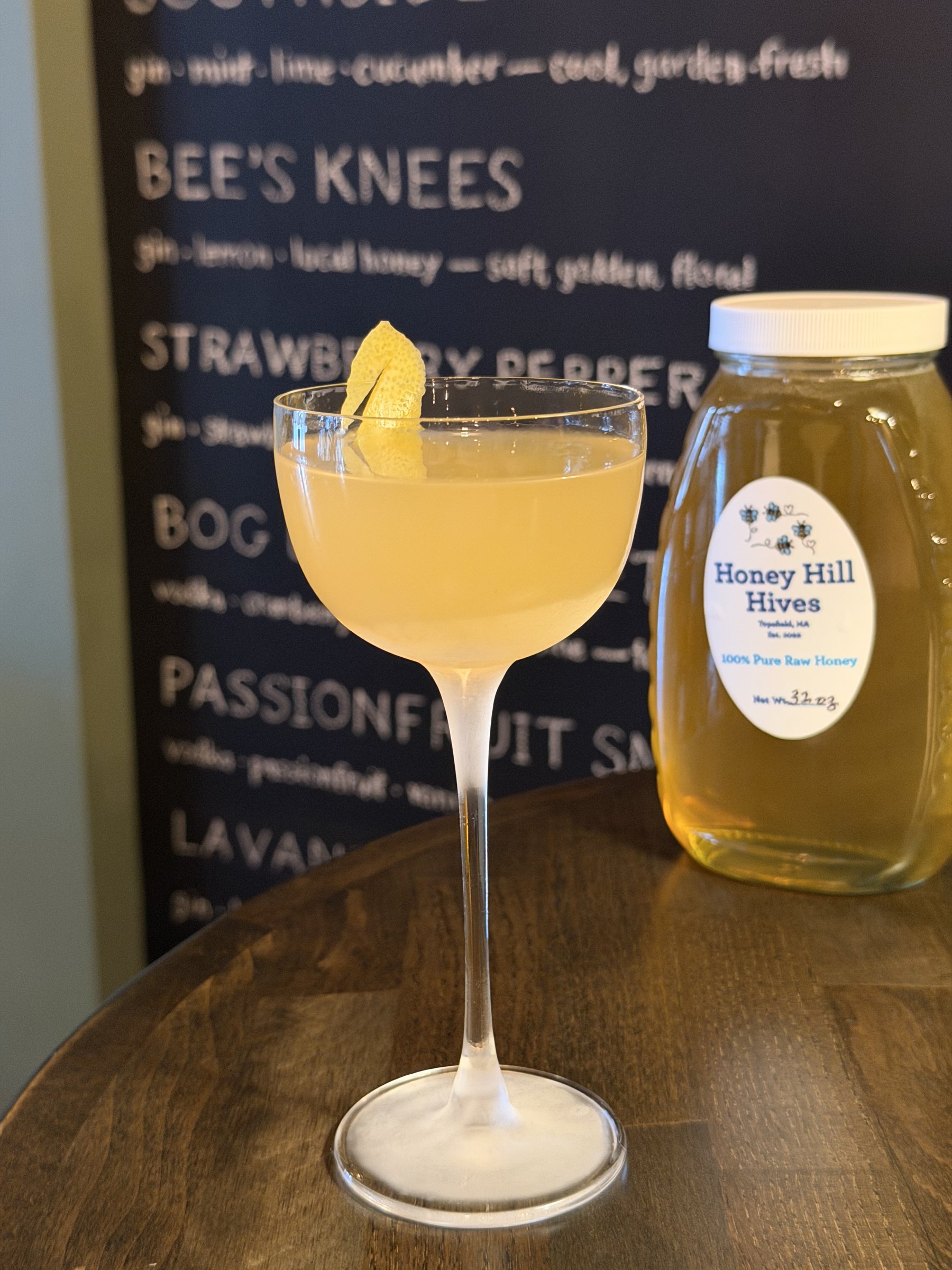 A Bee's Knees in a tall-stemmed coupe, local honey jar beside it
